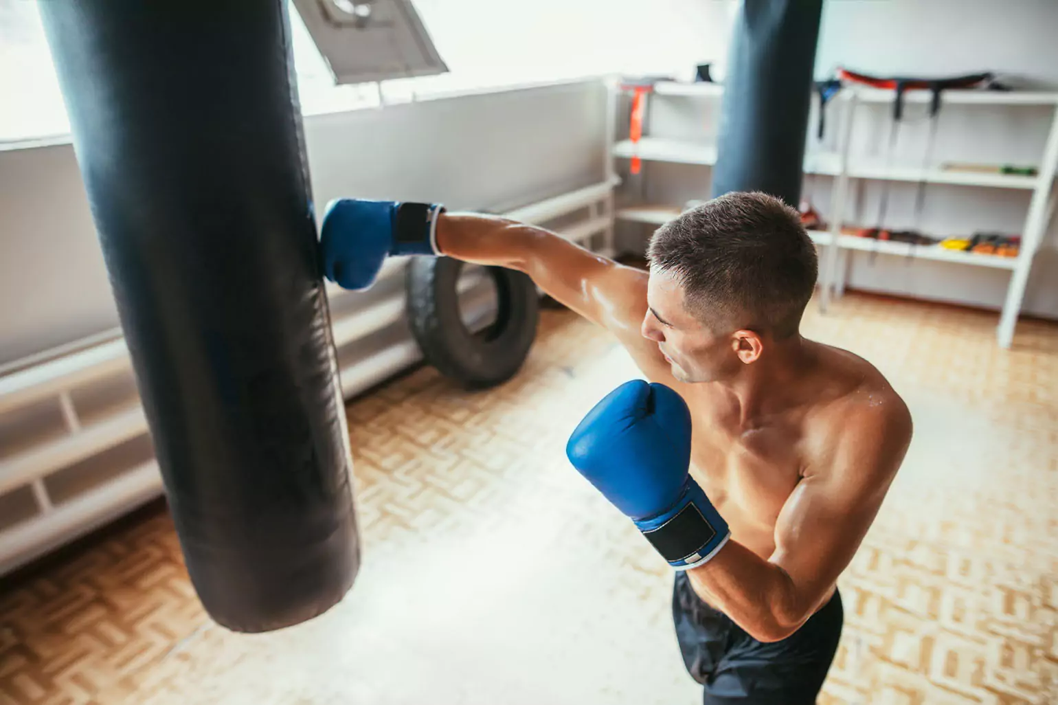 A person hits a boxing heavy bag in their garage.