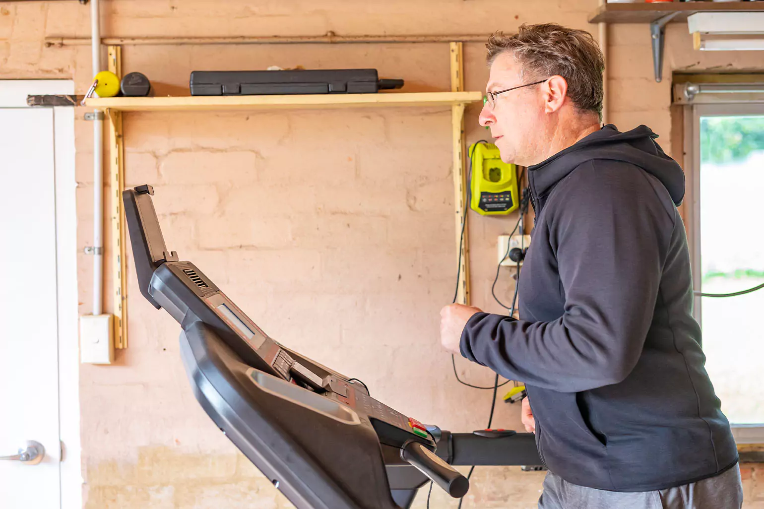 A man on running on a treadmill in the garage.