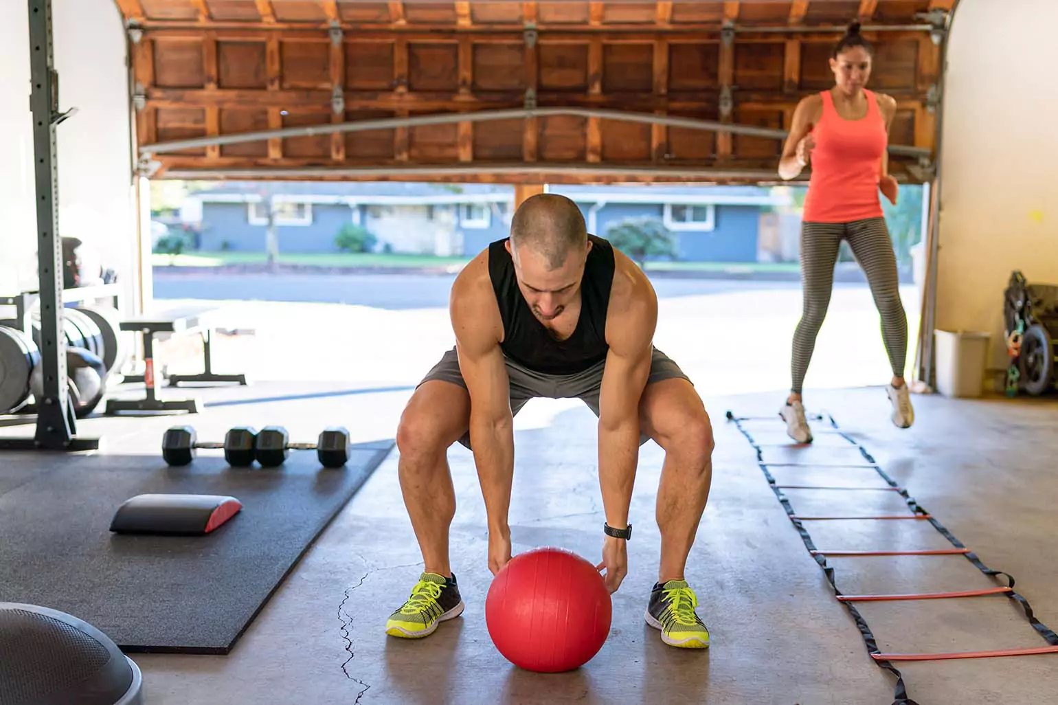 Two people exercising with a medicine ball and agility ladder.