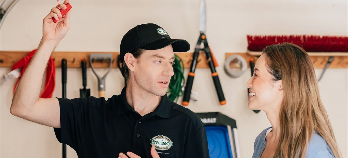 Garage door repair technician showing client how to use the garage door emergency release.