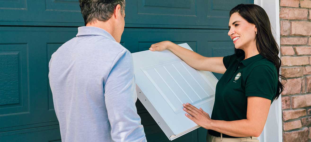 A garage door professional consults with a client on replacing their garage door.