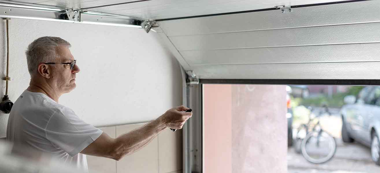 Man using garage door remote to open garage door.