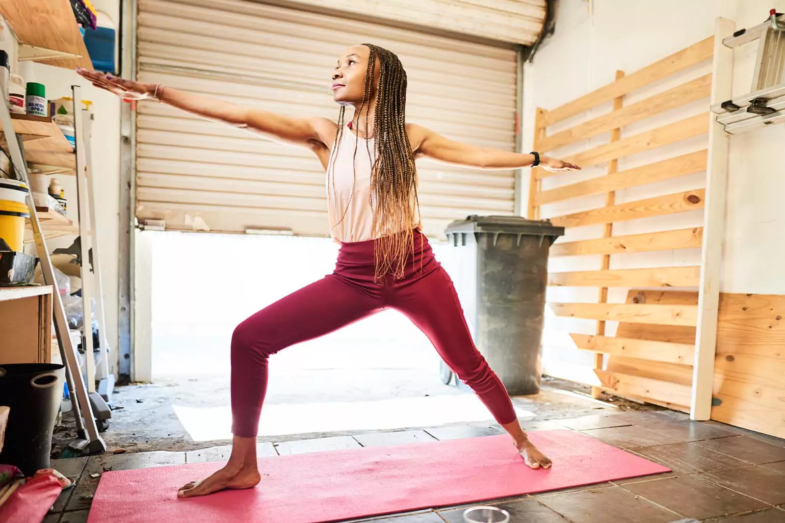 A woman practices yoga in a garage.