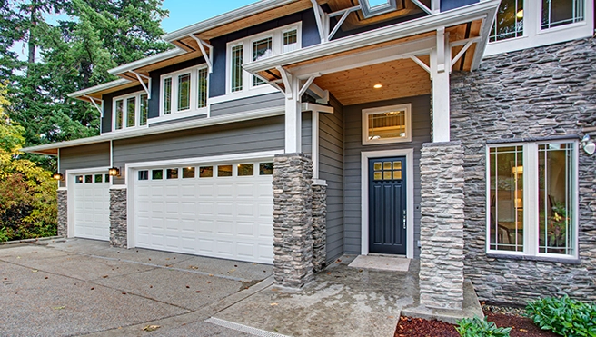 Two story house with three car garage and lights.