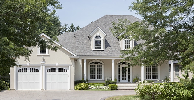 House with driveway and trees in front.