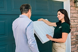 A PDS expert showing garage door plans to a client in front of a garage door.