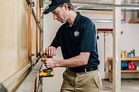 A PDS expert drilling into the back of a garage door.