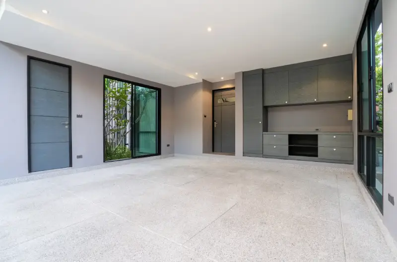 A remodeled garage with a cohesive design style including gray cabinetry, black accents, and a blue door.