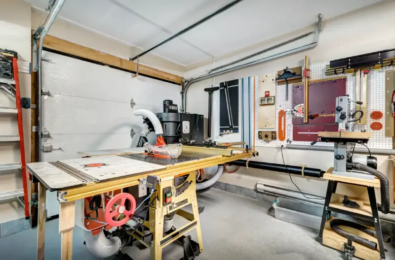 A remodeled garage with an impressive workshop consisting of various tools, equipment, and work stations.