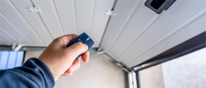 A person opening a garage door using a remote control.