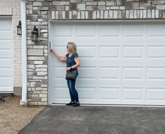 Mature, blond woman reaching up to enter in garage code | Precision Garage Door Service of Knoxville.