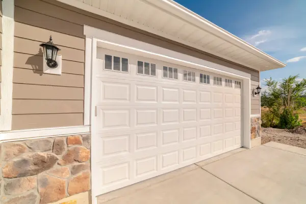 A new-looking white double garage door at the front of a suburban house. | Precision Garage Door Service of Chattanooga